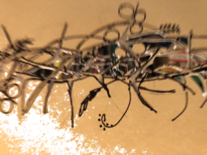 Ah, here it is, a nest for a raven's rest. With twigs of ash and oak and fig and banyan and baobab and thorny soetdoring twigs, and millet and barley and wheat and rye and gold flowers of the acacia tree, a nest of seeds a nest of bones and a nest of feathers, feathers that may or may not belong to this raven, or a raven before (of whom we do not speak) or perhaps she just stole them and took them for hers, she is a raven after all.
We look in between those twigs and we see a world of colours and light and black and shapes and things just waiting to be, things waiting that raven has stored away in her Raven's nest. Just for safekeeping, you know.
The picture is of the ravens nest horizontal across the page, nearer to the top, the nest is woven of branches with twigs and seads and feathers and pollen drawn in with black ink. There are cut-outs through the paper showing a multicoloured background if you look through. The paper on which the nest is drawn is a light brown, some sort of nearly yellow but not baby-poo colour and bright white.